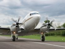 a small propeller plane on a runway with trees in the background