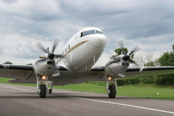 a small propeller plane on a runway with trees in the background