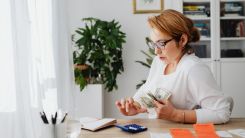 Woman Sitting at Desk Counting Money